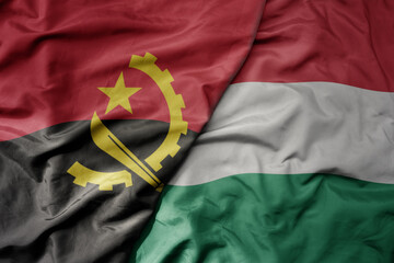 big waving national colorful flag of hungary and national flag of angola .