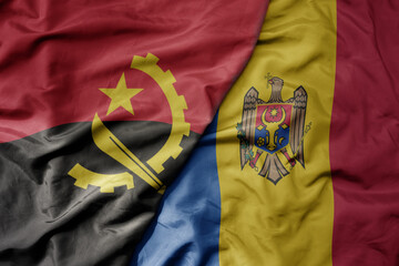 big waving national colorful flag of moldova and national flag of angola .