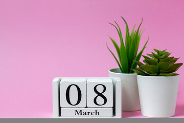 International Women's Day. March 8 on a wooden calendar on a pink background.