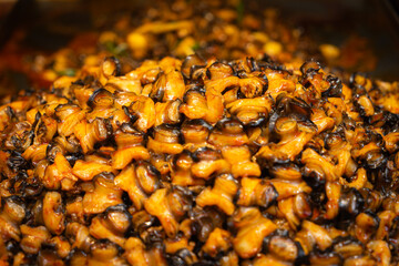 Close-up of golden brown fried snails, a popular street food in Wuchang , China. The image captures rich textures and colors.