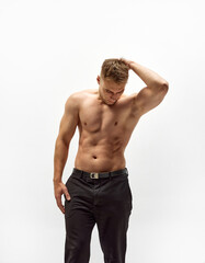 Fototapeta premium Handsome young man with shirtless, muscular body standing in pants isolated over white studio background. Relief torso. Concept of male beauty, body care, fitness, sport, healthy lifestyle