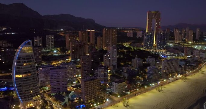 Aerial view of the coastal buildings at night in Benidorm, Spain. Beautiful blue hour aerial view of Benidorm. Peaceful beaches and smooth Mediterranean Sea with street lights glowing in the distance