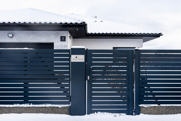 A modern gate with a letterbox and a wireless card reader, mounted in an anthracite panel fence,...