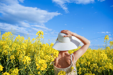 Background of a rear view of a woman with hat in a yellow flowers field. Spring and summer...