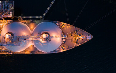 Aerial top down of Liquified Natural Gas LNG carrier moored to a small gas terminal. Top down view...