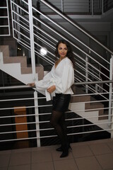 Attractive, pretty woman, fashionably dressed with a miniskirt and blouse, posing in a stairwell