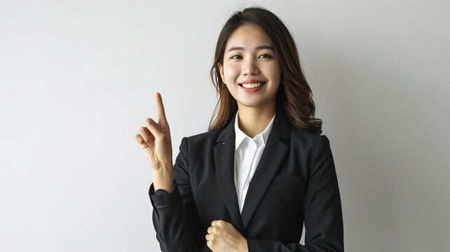 Successful upbeat smiling asian female manager, businesswoman in suit looking confident and pointing upper left corner with pleased grin