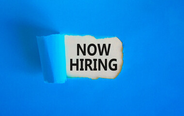 Now hiring symbol. Concept words Now hiring on beautiful white paper. Beautiful blue table blue background. Business marketing, motivational now hiring concept. Copy space.