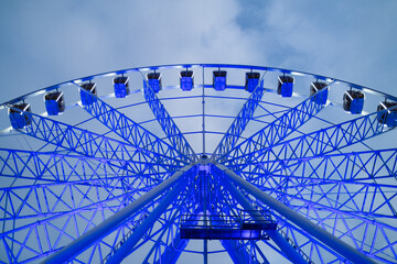 Underside view of colorful ferris wheel over evening sky at amusement park.