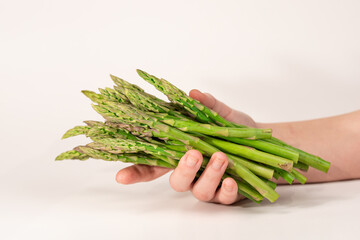 A bunch of asparagus held in a hand on a white background