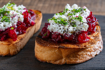 Toast from a slice of bread with white cream cheese, stewed beetroot pulp, seeds and green dill on...