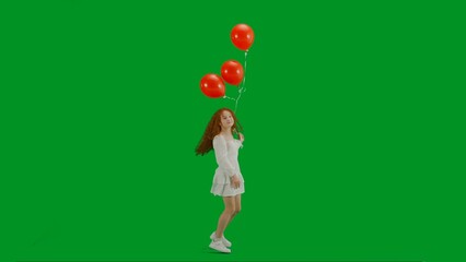 Little girl in white dress with red helium balloon on chroma key green screen isolated background looking at camera.