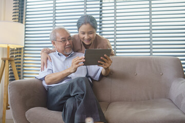 Asian grandfather and grandmother watching or meeting video call to family with digital tablet in...