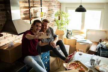 Poster Happy male gay couple taking selfie after moving in © Vorda Berge