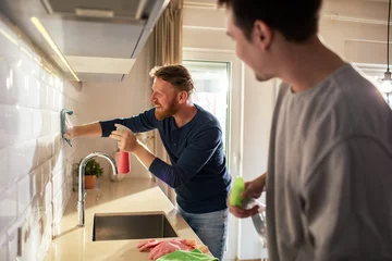 Foto op Canvas Gay couple cleaning modern kitchen at home © Vorda Berge