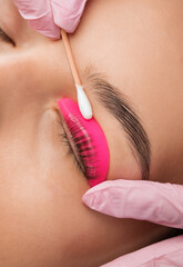 Make-up artist makes the procedure of lamination and dyeing of eyelashes to a beautiful woman in a...