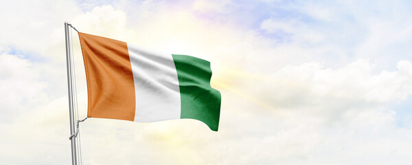 Cote d’Ivoire flag waving on sky background. 3D Rendering