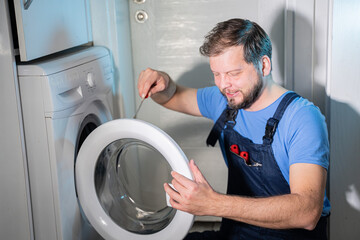 man a repairman repairs the washing machine at home
