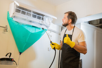 man worker from the cleaning service cleans the air conditioner