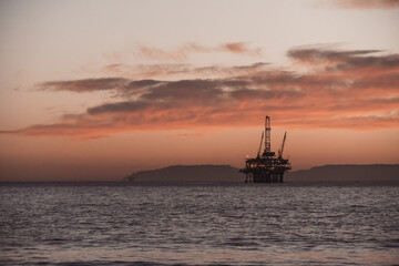 Fototapeta na wymiar oil rig at sunset beach