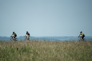 casual cyclists on a stone track in countryside, summer blue sky day