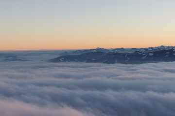 sunrise in winter landscape with snow covered mountains and sea of clouds