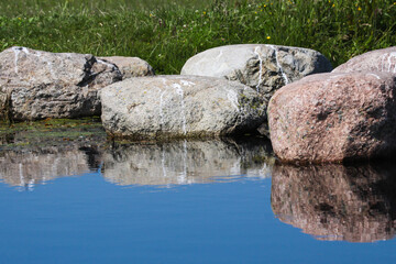 Couple of large boulders reflecting in water