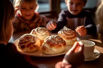 Foto op Aluminium Children at the table with Swedish semla buns with whipped cream © Alina