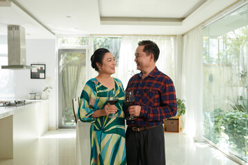 Fototapeta premium Happy Vietnamese senior couple drinking wine when celebrating anniversary at home
