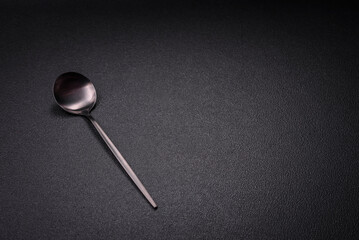 Empty metal spoon on dark textured concrete background