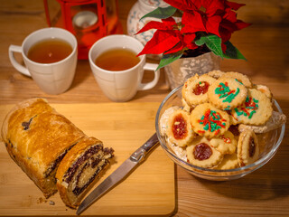 Christmas. Advent. Antique-style still life with candles, cake and poinsettia christmas star plant.