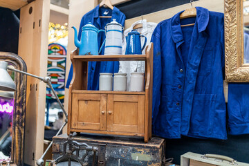 A blue jacket, white cans for bulk products on a small light chest of drawers from the seventies at...