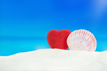 Red heart with conch on sand of beach behind sea. Valentine's Day, wedding, honeymoon, holiday in...