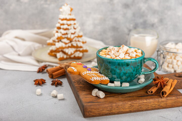 Hot drink with marshmallows and candy cane in  cup on a texture table.Cozy seasonal holidays.Hot cocoa with gingerbread Christmas cookies.Hot chocolate with marshmallow and spices.Copy space.