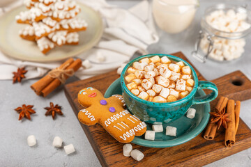 Hot drink with marshmallows and candy cane in  cup on a texture table.Cozy seasonal holidays.Hot cocoa with gingerbread Christmas cookies.Hot chocolate with marshmallow and spices.Copy space.