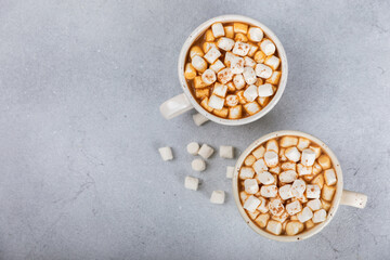 Hot drink with marshmallows and candy cane in  cup on a texture table.Cozy seasonal holidays.Hot cocoa with gingerbread Christmas cookies.Hot chocolate with marshmallow and spices.Copy space.
