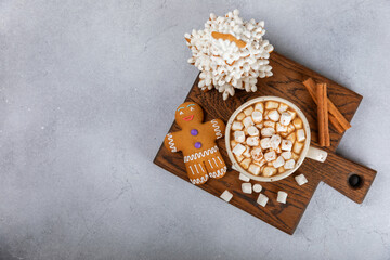 Hot drink with marshmallows and candy cane in  cup on a texture table.Cozy seasonal holidays.Hot cocoa with gingerbread Christmas cookies.Hot chocolate with marshmallow and spices.Copy space.
