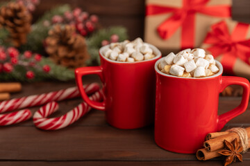 Hot drink with marshmallows and candy cane in  cup on a texture table.Cozy seasonal holidays.Hot cocoa with gingerbread Christmas cookies.Hot chocolate with marshmallow and spices.Copy space.