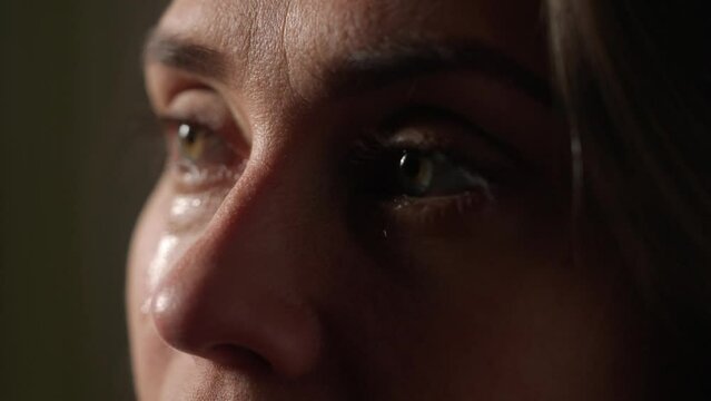 Portrait of attractive female model in negative mood. Extreme close up shot of woman face part in depressed mood, tears flowing down the face.