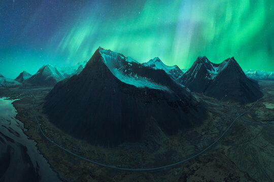 Northern Lights illuminating the sky above a black sand beach in Vík, Iceland