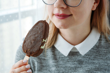 Woman in glasses eating ice cream on stick, sensual lips with frost chocolate, sexual eating for...