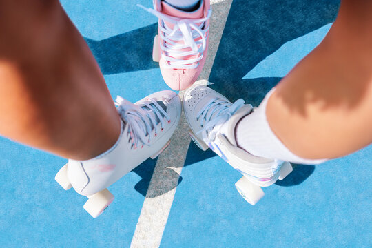 Crop young sportswomen legs in stylish roller skates on sports ground