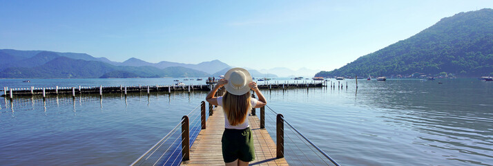 Holidays in Brazil. Panoramic banner view of young traveler woman walking on pier enjoying...