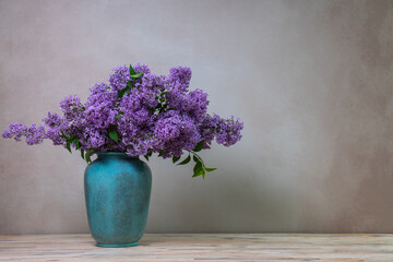 A huge bouquet of lilacs in a large vase isolated on a light gray background. Still life with flowers, plenty of space for text