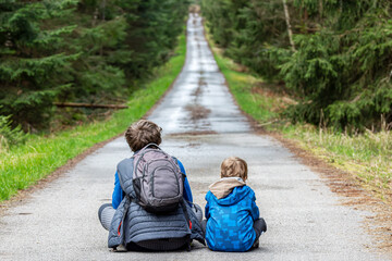 Two kids sitting in the middle of the road