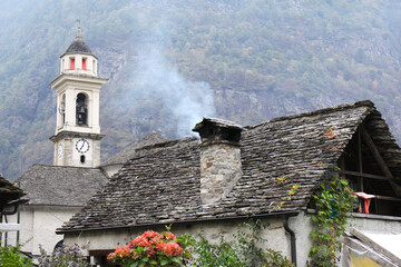 Stone cottage with a church tower in Sonogno, Lavertezzo Vally, Ticino, Switzerland