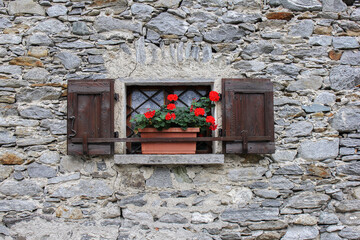Window with red geranium on a stone house