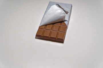 Close-up of brown Swiss milk Chocolate bar with white plastic wrapping against white background. Photo taken December 27th, 2023, Zurich, Switzerland.