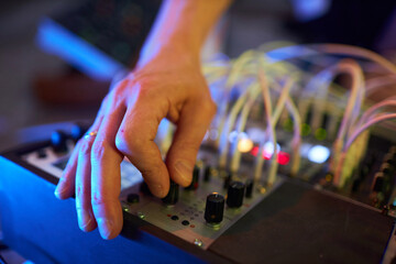 Close up shot of male hand turning knob on operating sound mixer board for combining different sounds during music recording