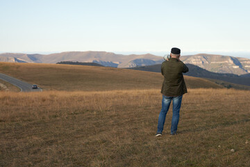 A lone photographer with a long lens on his camera against a mountainous terrain. Copy space.
